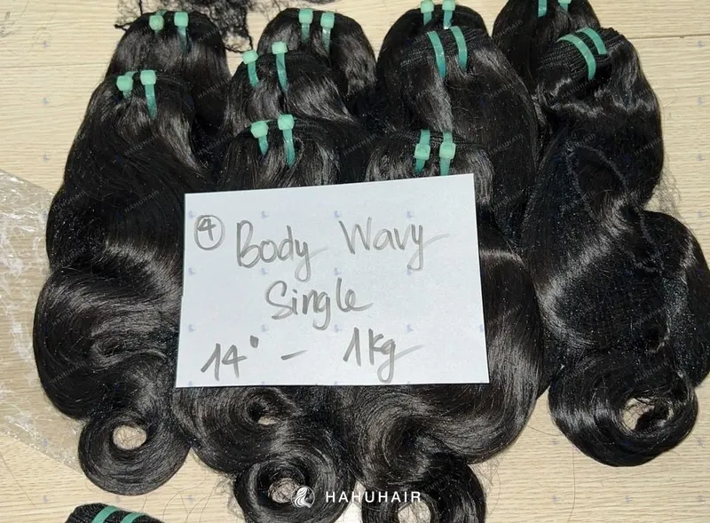 Волнистые трессы Body Wavy чёрного цвета на столе с рукописными подписями длины и градации