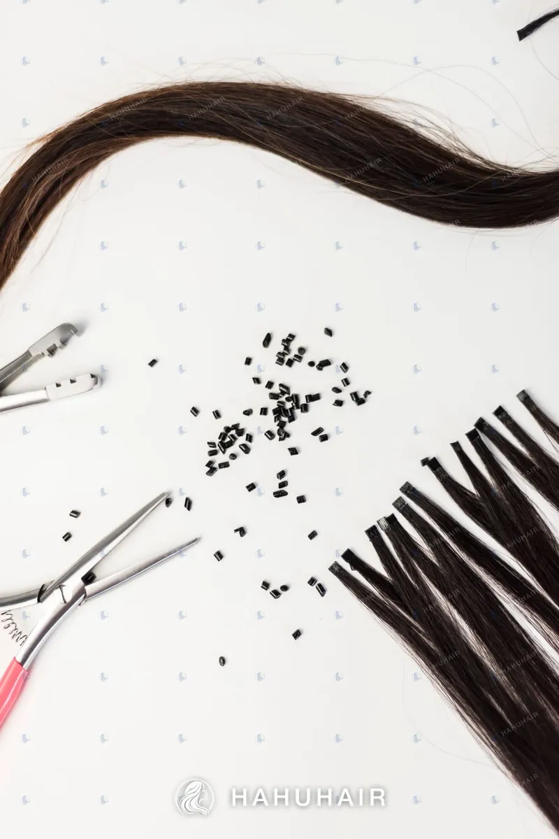 Dark brown hair strands with keratin beads and pliers on a white background