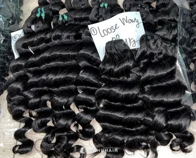 Loose wave black hair wefts on a table with handwritten length and grade labels