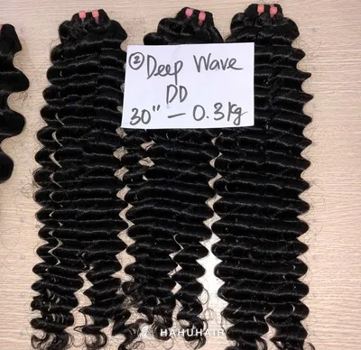 Deep wave black hair wefts on a table with handwritten length and grade labels