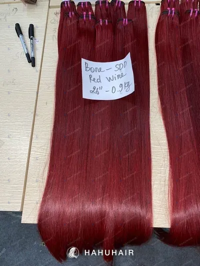 Bone straight red wine hair wefts on a table with handwritten length and grade labels
