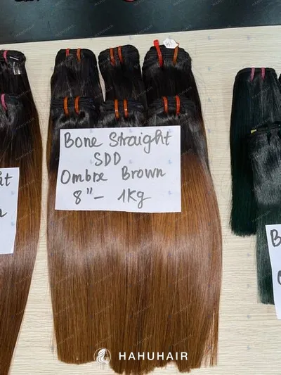 Bone straight brown ombre hair wefts on a table with handwritten length and grade labels