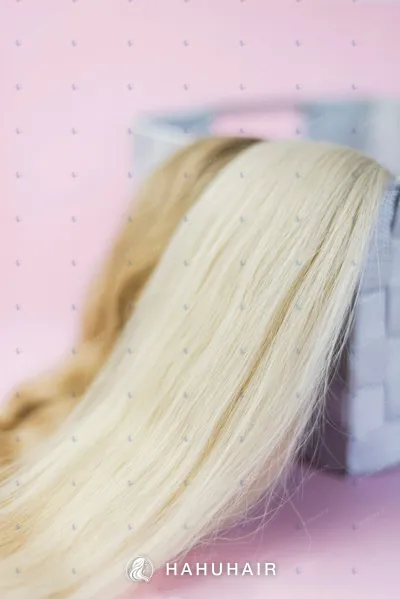 Long straight blonde hair draped over a woven basket on a pink background