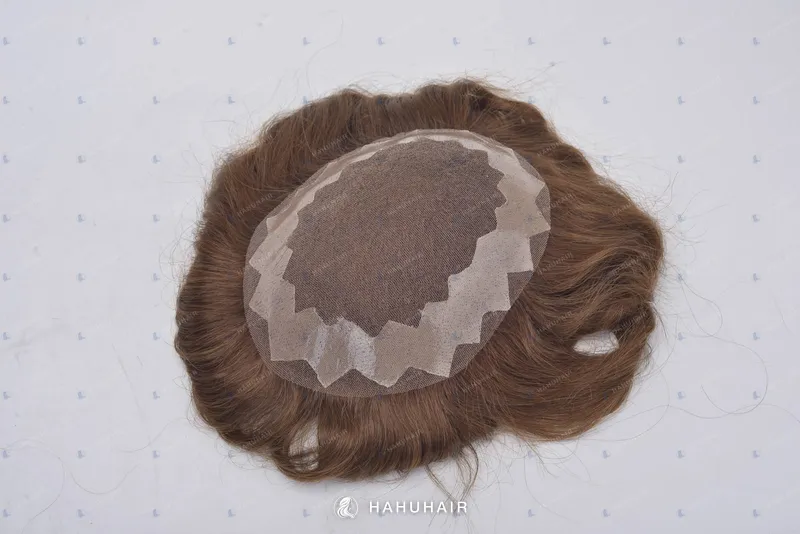 Close-up of a brown human-hair piece with a lace and mesh base on a white surface