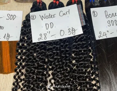 Water curly black hair wefts on a table with handwritten length and grade labels