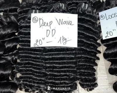 Deep wave black hair wefts on a table with handwritten length and grade labels