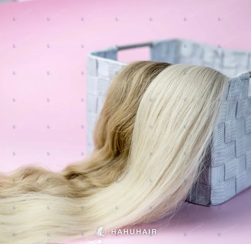 Long straight blonde and light-brown hair draped over a woven basket on a pink background