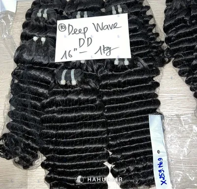 Deep wave black hair wefts on a table with handwritten length and grade labels