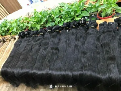 Natural straight black hair wefts on a table with handwritten length and grade labels
