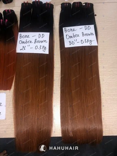 Bone straight brown ombre hair wefts on a table with handwritten length and grade labels