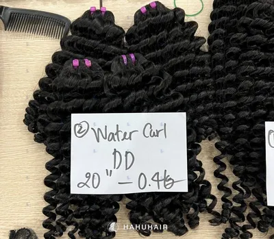 Water curly black hair wefts on a table with handwritten length and grade labels